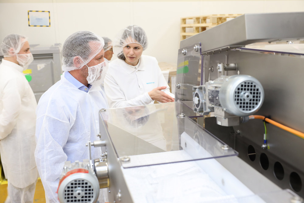 Brent Saunders at a health manufacturing lab speaking with a woman