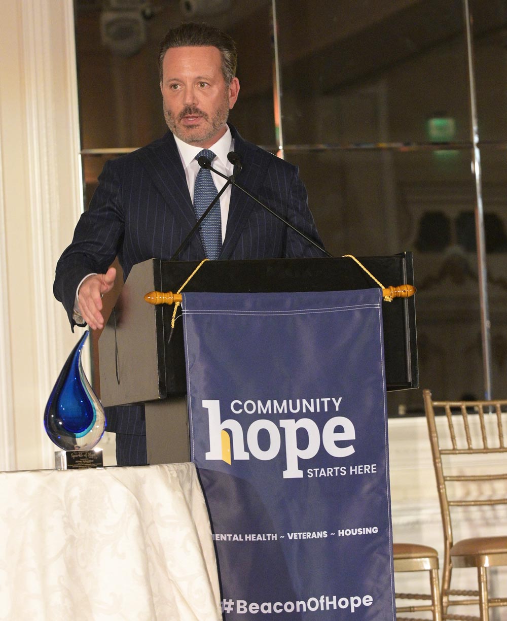 Brent Saunders at speaking at a podium at a Community Hope event